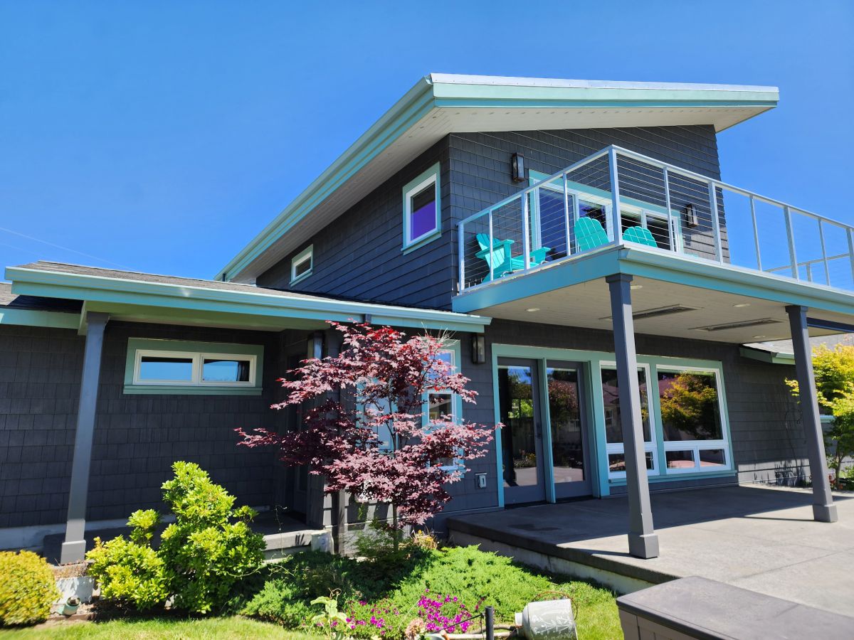 Modern coastal home with expansive glass balcony and Japanese maple