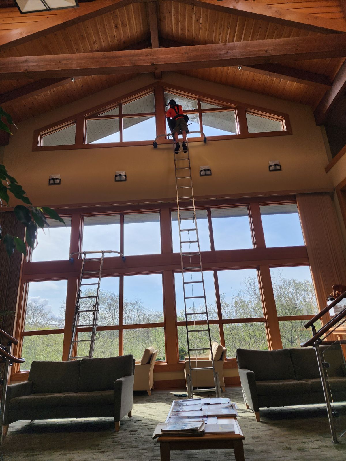Brookings Window Cleaning technician on a tall ladder cleaning vaulted great-room windows